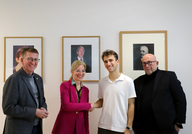 Drei Personen gratulieren Preistraeger