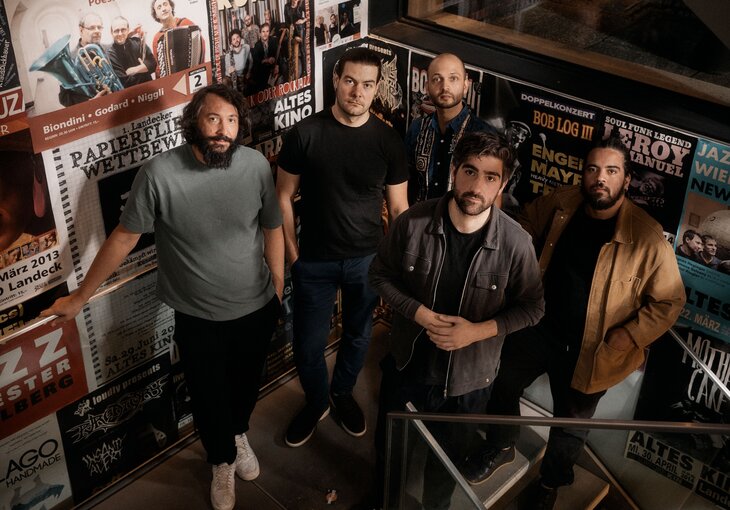 5 musiker vor plakatwand