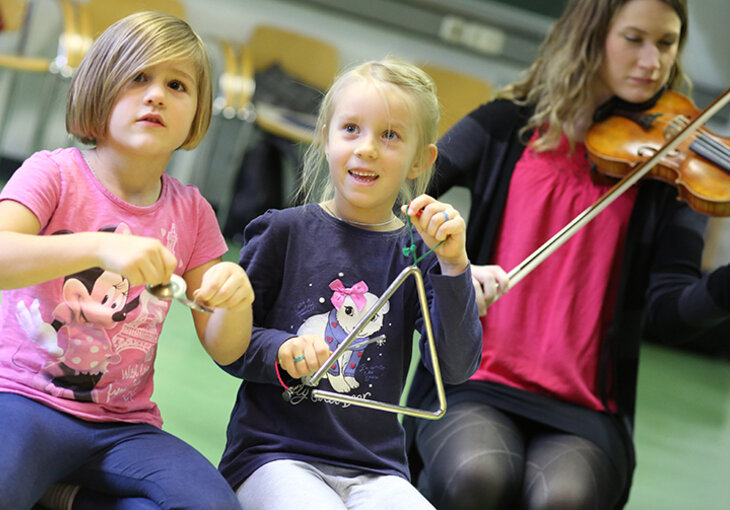 Kinder musizieren mit Triangel und Geige